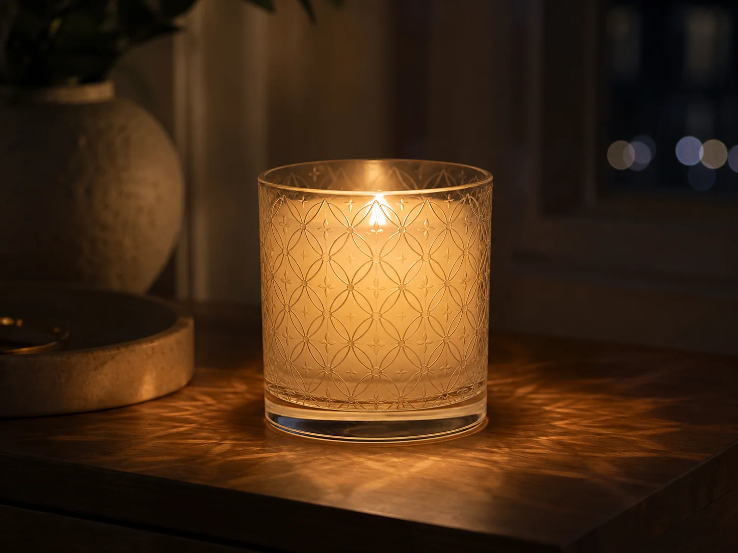 Récipient à bougie à motif gravé, allumé le soir dans une collection de bougies décoratives