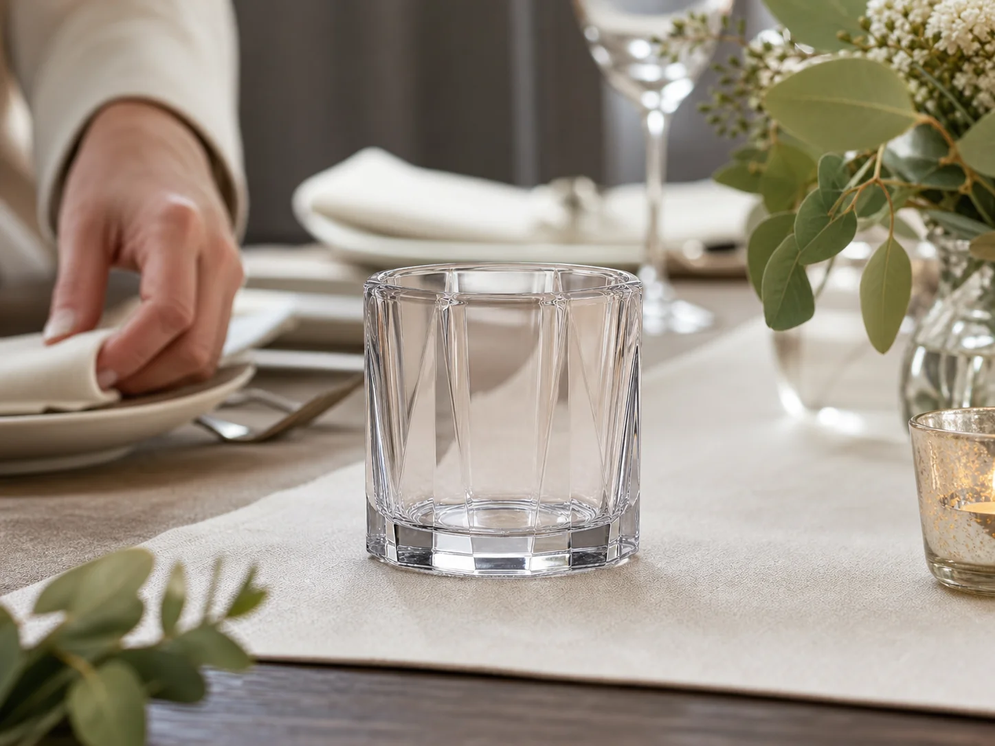 Pot à bougie facetté non allumé sur une table, avec des pans transparents visibles depuis le siège d’un invité