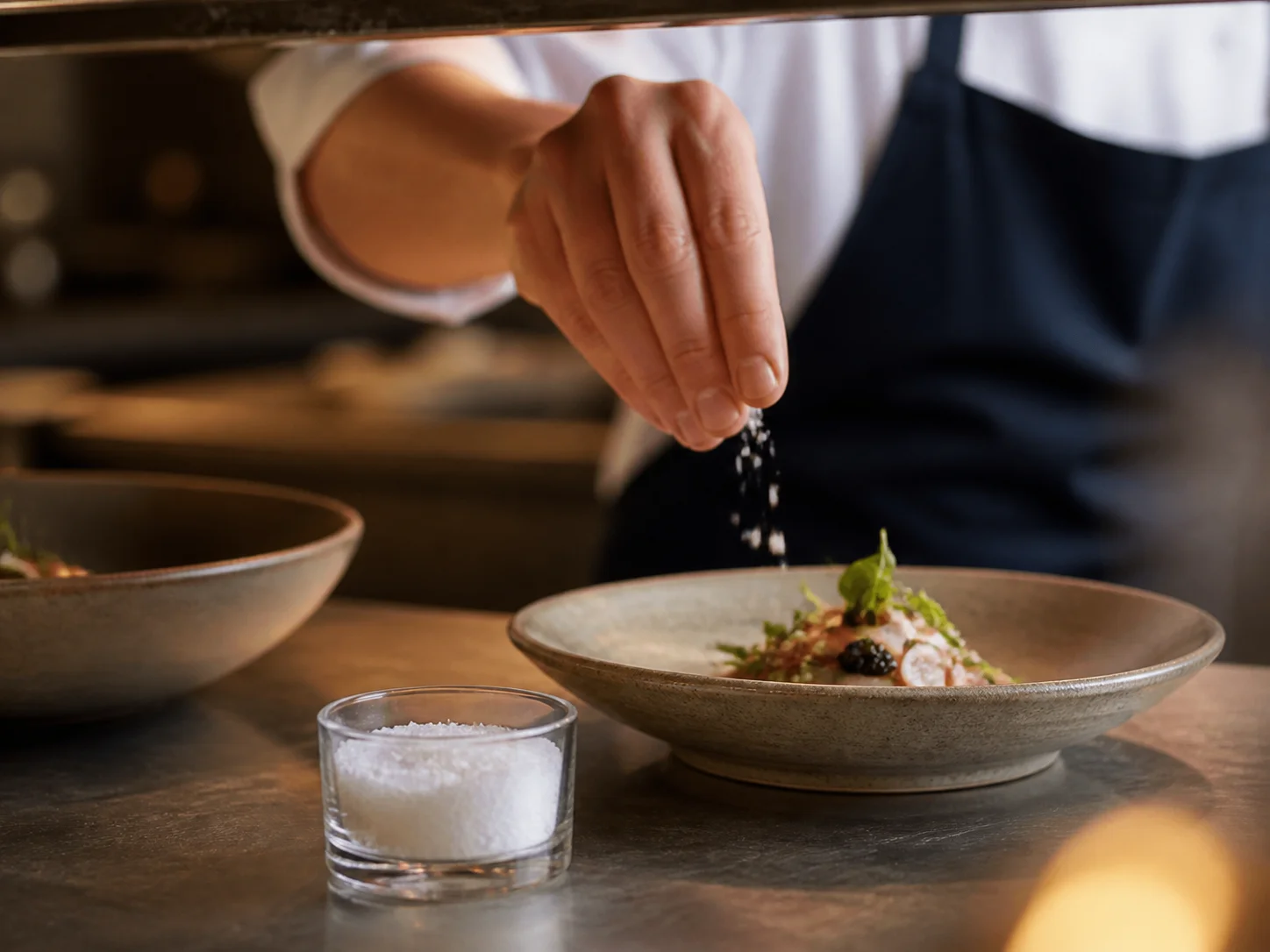 Salière utilisée au passe du chef, pour un menu dégustation et en service partagé à table, dans un contexte de restauration